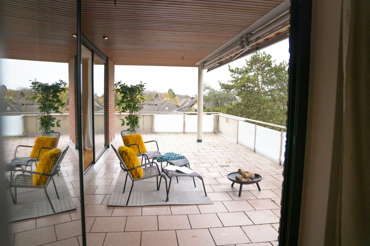 Moderne Balkonmöbel mit gelben Kissen und Feuerstelle.