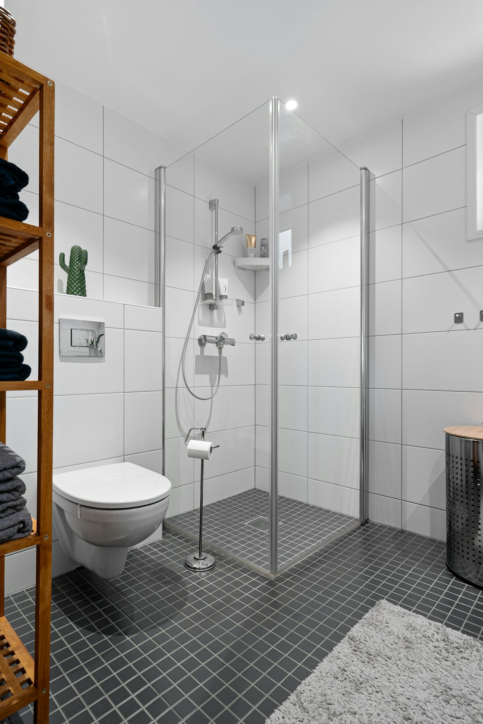 Modernes Badezimmer mit Dusche und ordentlich gestapelten Handtüchern.
