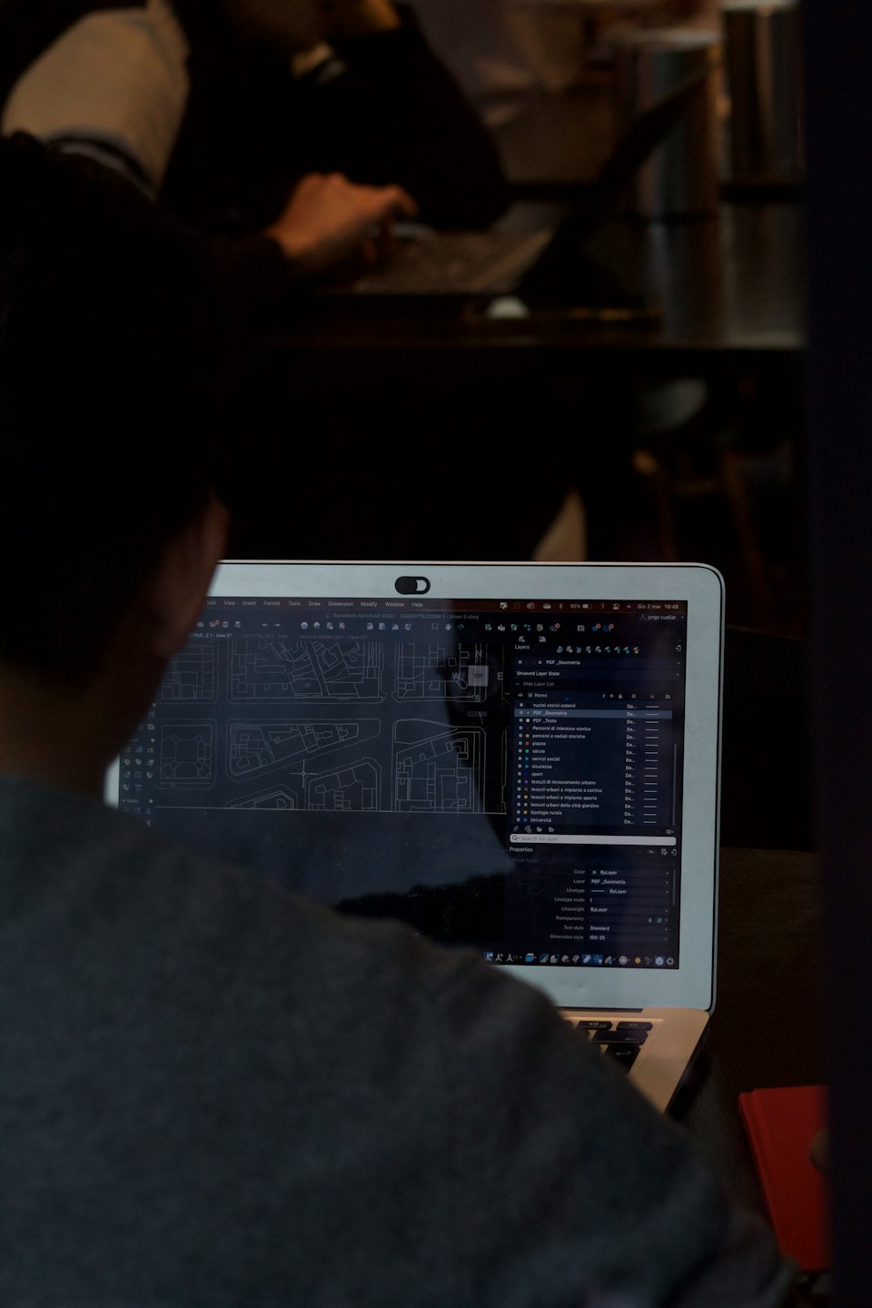 Person arbeitet an Architekturplänen auf einem Laptop.